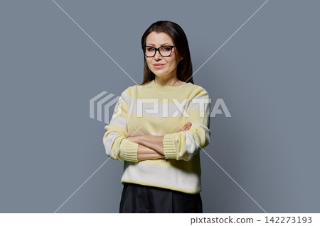 Confident smiling mature woman in glasses with arms crossed studio portrait 142273193