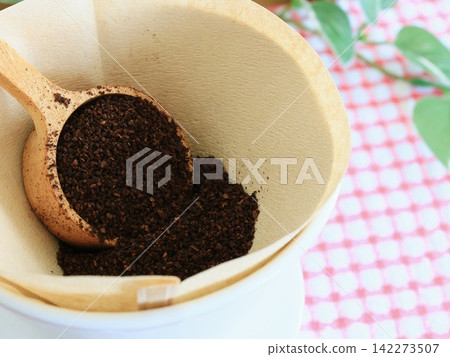 Ground coffee in a paper filter and a wooden spoon Ground coffee in a paper filter and a wooden spoon 142273507