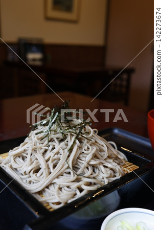 A large serving of zaru soba (cold buckwheat noodles). 100% buckwheat noodles. Topped with seaweed. Served in a black bamboo basket. A large serving of zaru soba (cold buckwheat noodles). 100% buckwheat noodles. Topped with seaweed. Served in a black bamboo basket. 142273674
