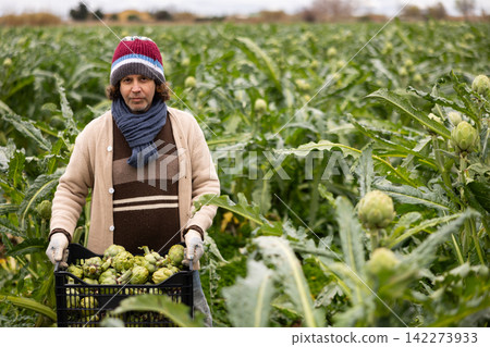 Middle-aged man holding plastic crate with arti, hoke Middle-aged man holding plastic crate with arti, hoke 142273933