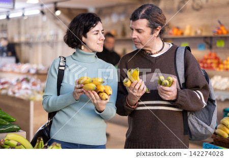 Couple man and woman choosing bananas in vegetable shop 142274028