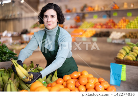 Woman shop seller puts banana goods on display case Woman shop seller puts banana goods on display case 142274036