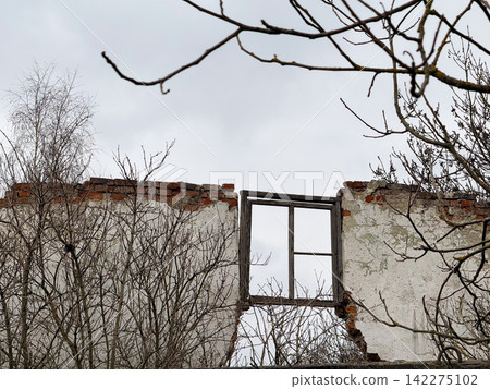 Ruined abandoned building wall with empty window frame Ruined abandoned building wall with empty window frame 142275102