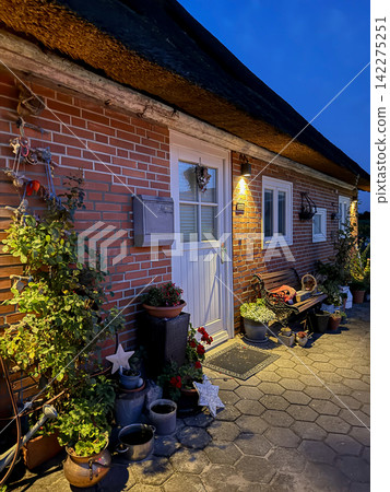 Cozy cottage entrance with thatched roof at dusk Cozy cottage entrance with thatched roof at dusk 142275251