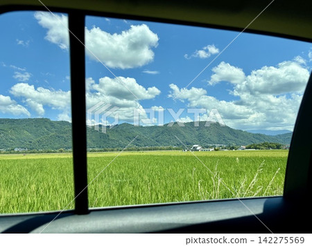 從車窗望出去,可以看到藍天、山脈和鬱鬱蔥蔥的鄉村景色(途經安曇野的風景優美的駕車之旅)。 從車窗望出去,可以看到藍天、山脈和鬱鬱蔥蔥的鄉村景色(途經安曇野的風景優美的駕車之旅)。 142275569