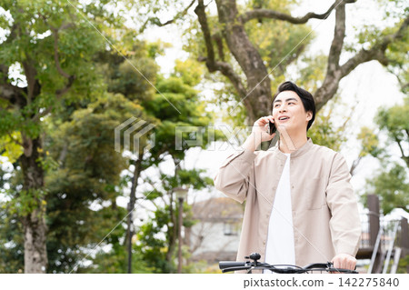 A man riding a bicycle while talking on the phone is a social issue. A man riding a bicycle while talking on the phone is a social issue. 142275840