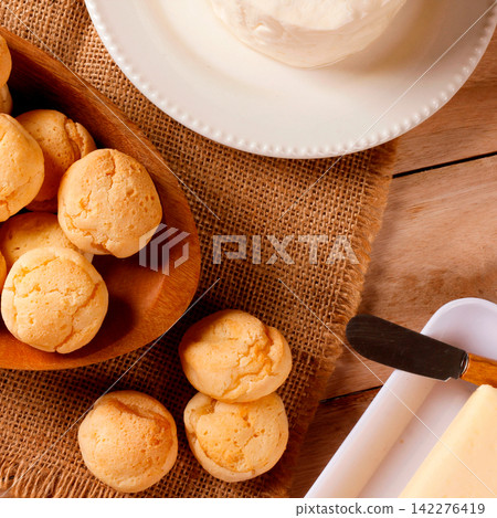 Homemade Brazilian cheese bread served on a wooden platter, accompanied by fresh Minas cheese, butter, and black coffee Homemade Brazilian cheese bread served on a wooden platter, accompanied by fresh Minas cheese, butter, and black coffee 142276419