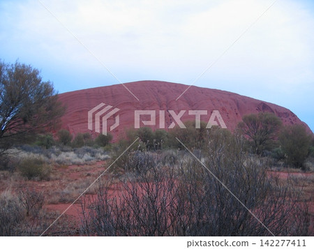 Ayers Rock before the morning light hits it, with clouds and blue sky stretching out above (Australia) 142277411