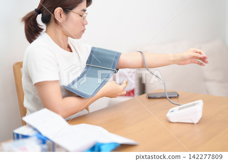 woman checking Blood pressure by Blood pressure monitor with Cuff. Systolic, SYS, Diastolic, DIA, Pulse, Hypertension, Hypotension, Heart rate, Cardiovascular Disease and May World hypertension day woman checking Blood pressure by Blood pressure monitor with Cuff. Systolic, SYS, Diastolic, DIA, Pulse, Hypertension, Hypotension, Heart rate, Cardiovascular Disease and May World hypertension day 142277809