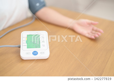 woman checking Blood pressure by Blood pressure monitor with Cuff. Systolic, SYS, Diastolic, DIA, Pulse, Hypertension, Hypotension, Heart rate, Cardiovascular Disease and May World hypertension day 142277819
