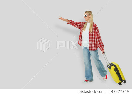 Travel. Young woman holds bright yellow suitcase, signaling her travel plans Travel. Young woman holds bright yellow suitcase, signaling her travel plans 142277849