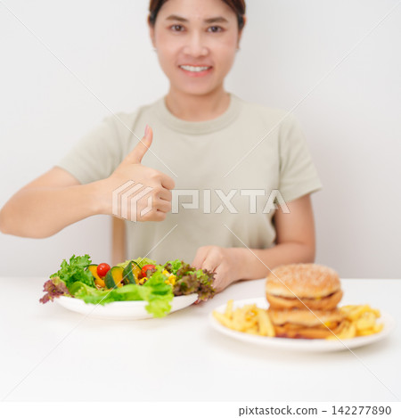 happy woman choose vegetables Salad and thumbs up gesture. Healthy and Unhealthy Food Choice, Calories and Nutrition of vegetables and Hamburger. dieting, weight loss control, junk food and lifestyle happy woman choose vegetables Salad and thumbs up gesture. Healthy and Unhealthy Food Choice, Calories and Nutrition of vegetables and Hamburger. dieting, weight loss control, junk food and lifestyle 142277890