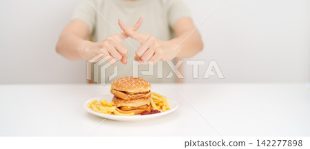 Unhappy woman showing Rejecting and refusing with Juicy beef burger, potato chips and carbonated Soft drinks. Unhealthy, High calorie, Fast food craving, Obesity, diet, weight loss and junk food Unhappy woman showing Rejecting and refusing with Juicy beef burger, potato chips and carbonated Soft drinks. Unhealthy, High calorie, Fast food craving, Obesity, diet, weight loss and junk food 142277898