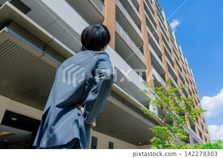 A salaryman looking up at an apartment building A salaryman looking up at an apartment building 142278303