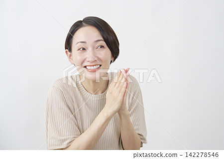 A woman in her 40s with a smiling face against a white background, making a wish. A woman in her 40s with a smiling face against a white background, making a wish. 142278546