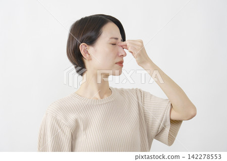 A woman in her 40s using a white background to soothe her tired eyes. A woman in her 40s using a white background to soothe her tired eyes. 142278553