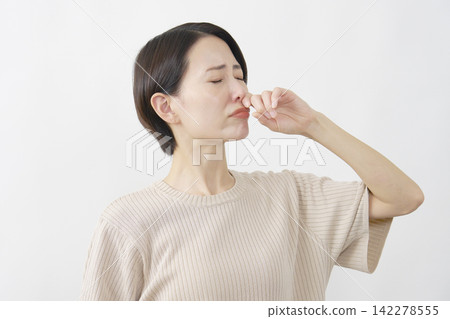 一位四十多歲的女性，在白色背景下，因鼻塞而感到不適。 142278555