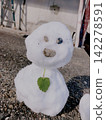 冬日景色中，一個胸前停著一片樹葉的可愛雪人。 142278591
