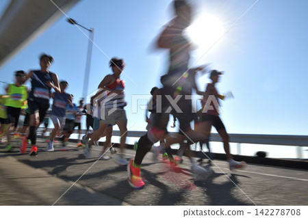 Marathon: Marathon runners running up a hill with slow shutter Marathon: Marathon runners running up a hill with slow shutter 142278708
