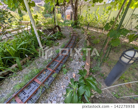綠樹成蔭的花園裡鋪設著微型鐵路軌道。 綠樹成蔭的花園裡鋪設著微型鐵路軌道。 142278938