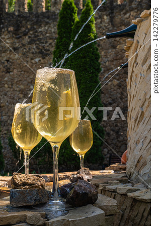 Close up of white wine pouring into glasses at fountain Close up of white wine pouring into glasses at fountain 142279776