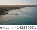 Aerial of sandy beach with wooden pier leading over the caribbean sea at sunset 142280031