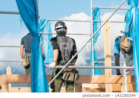 木匠們正在進行新房的框架搭建和屋頂抬升工作。 木匠們正在進行新房的框架搭建和屋頂抬升工作。 142280294