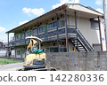 An old apartment and an excavator An old apartment and an excavator 142280336