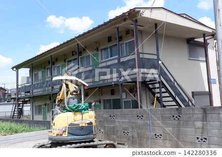 An old apartment and an excavator An old apartment and an excavator 142280336