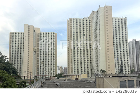 Hong Kong residential apartment buildings under a cloudy sky in an urban setting Hong Kong residential apartment buildings under a cloudy sky in an urban setting 142280339