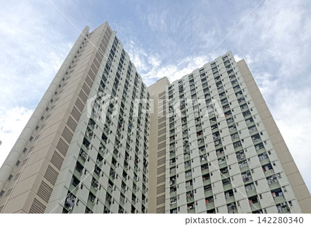 Hong Kong Towering residential building with many windows against cloudy sky Hong Kong Towering residential building with many windows against cloudy sky 142280340