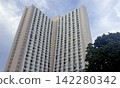 Towering residential building with many windows against a cloudy sky Towering residential building with many windows against a cloudy sky 142280342