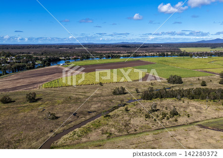 Aerial view of lush green rural land alongside the Clarence River at Maclean, showcasing open farmland, riverside vegetation and the broad waterway within the Northern Rivers region of NSW, Australia Aerial view of lush green rural land alongside the Clarence River at Maclean, showcasing open farmland, riverside vegetation and the broad waterway within the Northern Rivers region of NSW, Australia 142280372