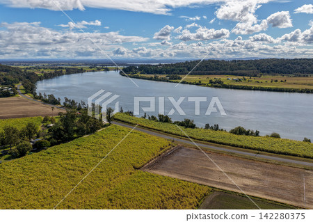 Aerial view of lush green rural land alongside the Clarence River at Maclean, showcasing open farmland, riverside vegetation and the broad waterway within the Northern Rivers region of NSW, Australia. Aerial view of lush green rural land alongside the Clarence River at Maclean, showcasing open farmland, riverside vegetation and the broad waterway within the Northern Rivers region of NSW, Australia. 142280375