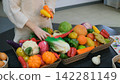 Child girl playing indoors, arranging colorful toy vegetables and fruits in a basket for pretend cooking. Imaginative play concept 142281149