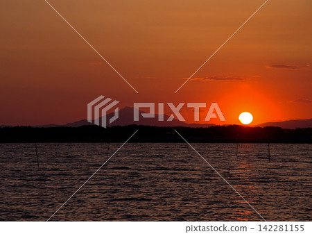 茨城縣日沼湖的日落。筑波山的輪廓與橙色的夕陽交相輝映,構成了一幅美麗而令人印象深刻的景象。 茨城縣日沼湖的日落。筑波山的輪廓與橙色的夕陽交相輝映,構成了一幅美麗而令人印象深刻的景象。 142281155