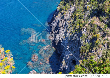 Rocky cliff with underwater rocks and rugged cliff texture in strong direct sunlight Rocky cliff with underwater rocks and rugged cliff texture in strong direct sunlight 142281596