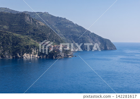 Manarola in Italy, including settlement dwarfed by steep coastal landscape Manarola in Italy, including settlement dwarfed by steep coastal landscape 142281617