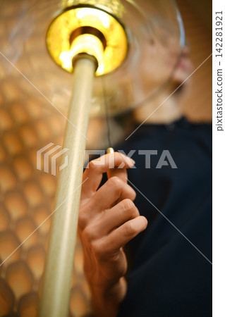 Bottom view of a woman turning on a floor lamp 142281921