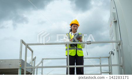 Asian Female Engineer Inspecting Wind Turbine System on Platform With Tablet Asian Female Engineer Inspecting Wind Turbine System on Platform With Tablet 142283171