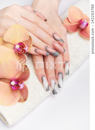 Woman's hands receiving professional manicure on towel with orchids 142283760