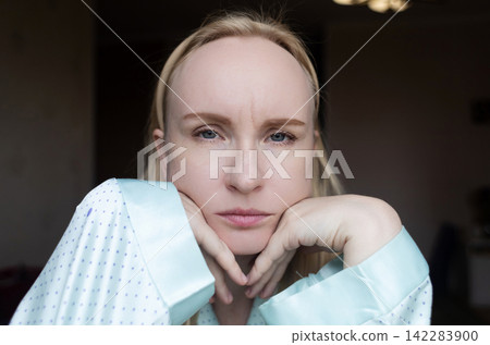 A adult woman touching forehead wrinkle between eyebrows and looking in mirror. She is concerned about aging lines, frown lines, facial skin care, and botox injections. A adult woman touching forehead wrinkle between eyebrows and looking in mirror. She is concerned about aging lines, frown lines, facial skin care, and botox injections. 142283900