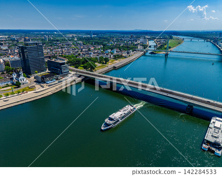 High angle wide horizontal aerial drone photograph of Rhine river, passenger cruise ship, Deutzer Bridge, Severins Bridge, and city skyline in Cologne, North Rhine-Westphalia, Germany, Central Europe 142284533