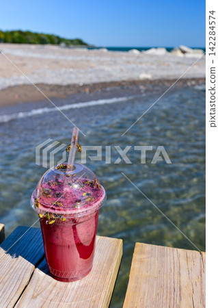 Bees swarming around a pink smoothie Bees swarming around a pink smoothie 142284574