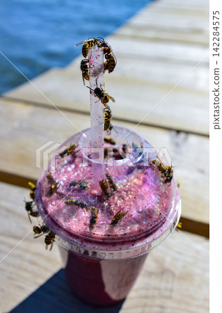 Bees swarming around a pink smoothie Bees swarming around a pink smoothie 142284575
