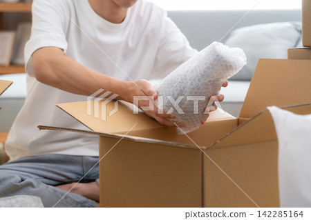 一位年輕人正在收拾行李準備搬家。 142285164