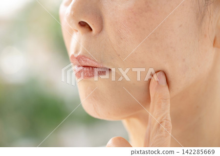 一位女子憂心忡忡地撫摸著自己的臉頰。 142285669