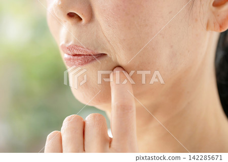一位女子憂心忡忡地撫摸著自己的臉頰。 142285671