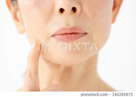 A woman touches her cheek, looking troubled. (Front view) A woman touches her cheek, looking troubled. (Front view) 142285673