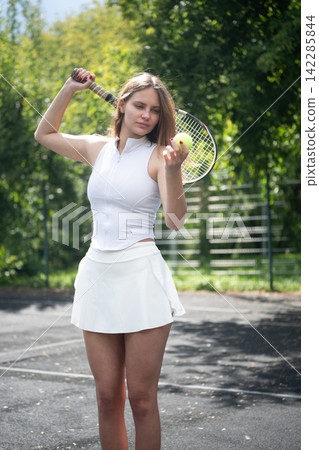 Focused female tennis player examining ball before match Focused female tennis player examining ball before match 142285844